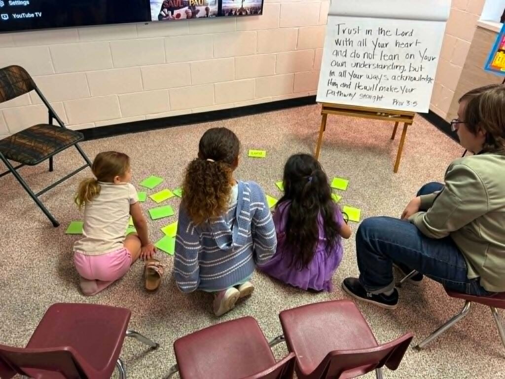 Children arranging Bible verse word cards on the floor